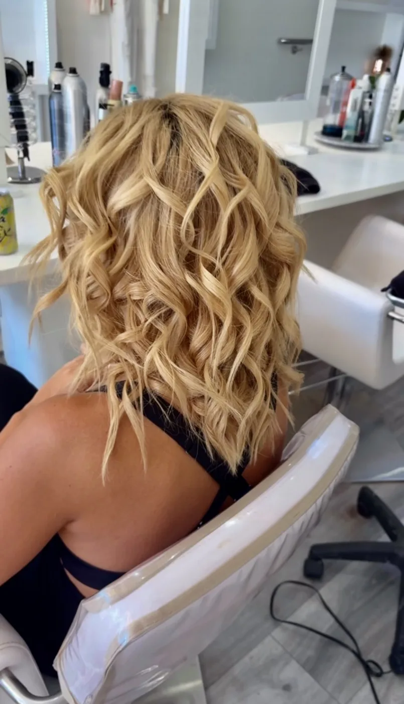 Bright blonde shoulder-length hair styled in loose defined curls