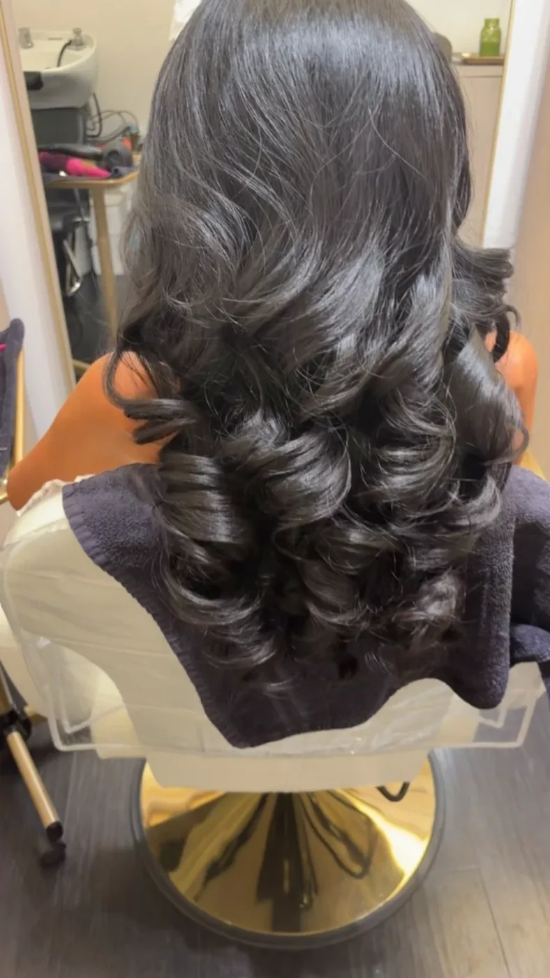 Jet black hair set in glossy hollywood curls at the salon chair